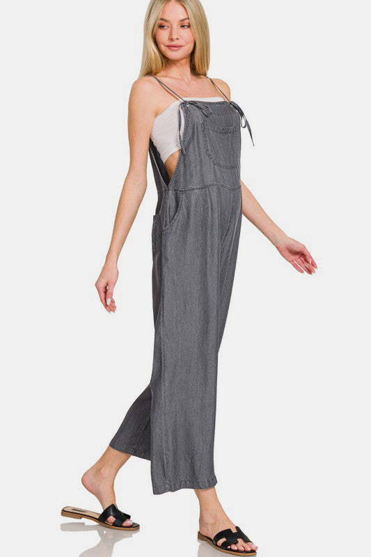 Trendy woman in washed adjustable strap wide leg denim overalls, styled for a casual chic look.