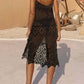 Woman wearing a black openwork scoop neck spaghetti strap cover-up dress with sandals in an outdoor setting