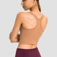 Back view of a woman wearing a Millennia Racerback Sports Bra in a tan color, showcasing its sleek design and sporty style.