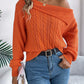 Woman wearing Bella Road Cable-Knit One Shoulder Long Sleeve Sweater in orange, paired with jeans and belt.