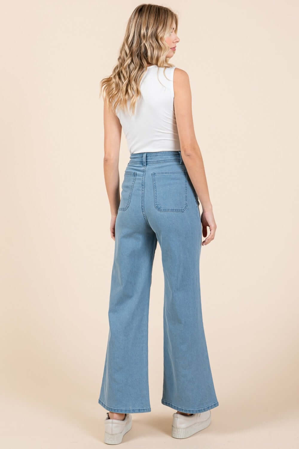 Woman wearing Mittoshop high-waist wide-leg jeans, showcasing the flattering silhouette and back patch pockets against a neutral background.