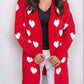 Woman wearing Bella Road Heart Open Front Long Sleeve Cardigan with white heart patterns and black top.