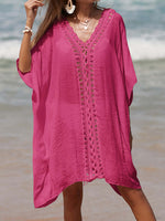 Woman wearing a pink cutout V-neck three-quarter sleeve cover up, made of sheer fabric with openwork design, standing on a beach.