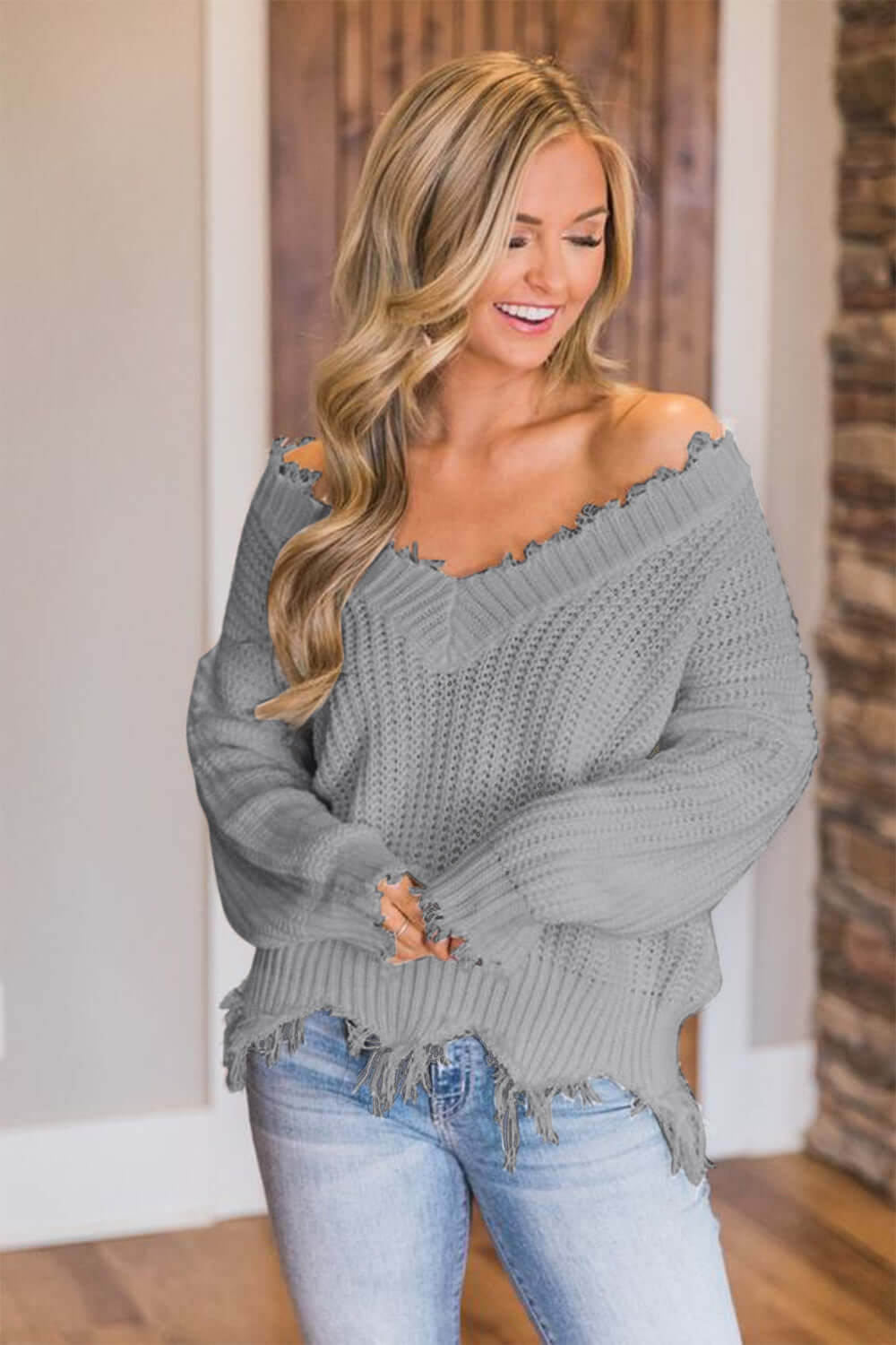 Woman wearing Bella Road Frayed Hem Dropped Shoulder Sweater in stylish gray, looking chic and cozy in a casual setting.