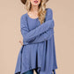 Woman wearing Ces Femme asymmetrical long sleeve top in blue with a hat, showcasing drop sleeves and a relaxed fit.