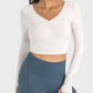 Millennia Ruched Cropped Long Sleeve Sports Top in cream, paired with stylish high-waisted leggings for an active look.