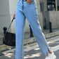 Fashionable woman in light wash denim side slit jeans and white sneakers, perfect for casual outings.