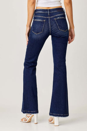 Woman wearing RISEN Full Size Low Rise Flare Jeans in dark wash, showcasing retro style and flattering silhouette from back view.