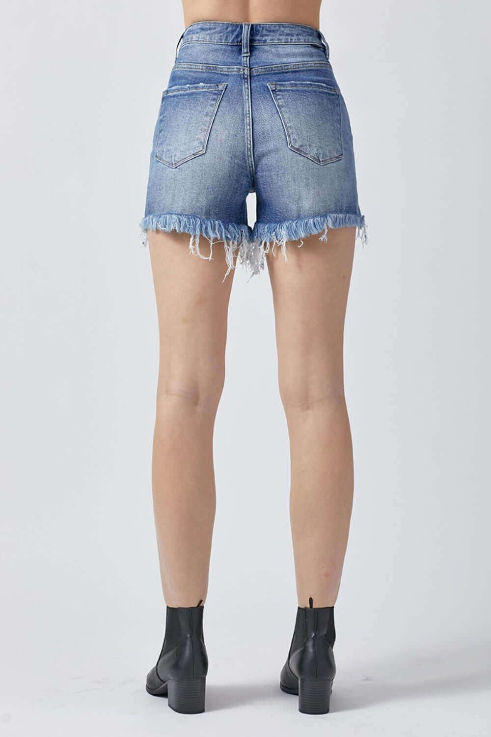 Back view of Raw Hem Asymmetrical Waist Denim Shorts by Risen Jeans showing edgy style with frayed details.