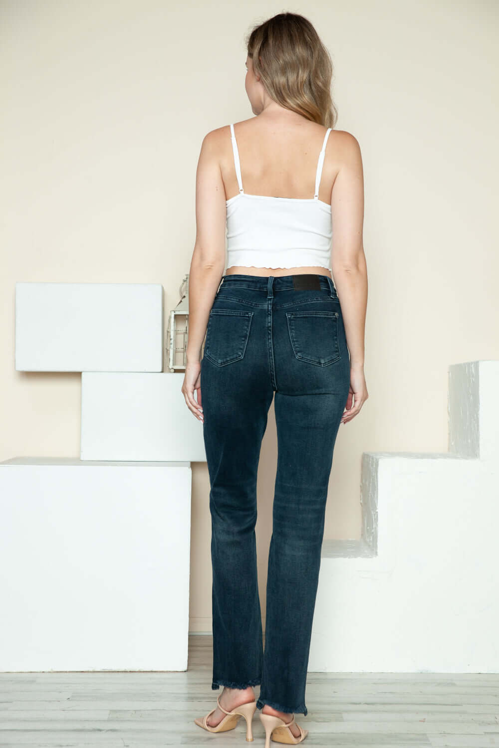 Woman wearing Judy Blue button fly hem destroy straight jeans, showcasing the back fit and stylish distressed detail.