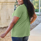 Woman wearing green Basic Bae Bamboo V-Neck Short Sleeve T-Shirt walking outdoors.