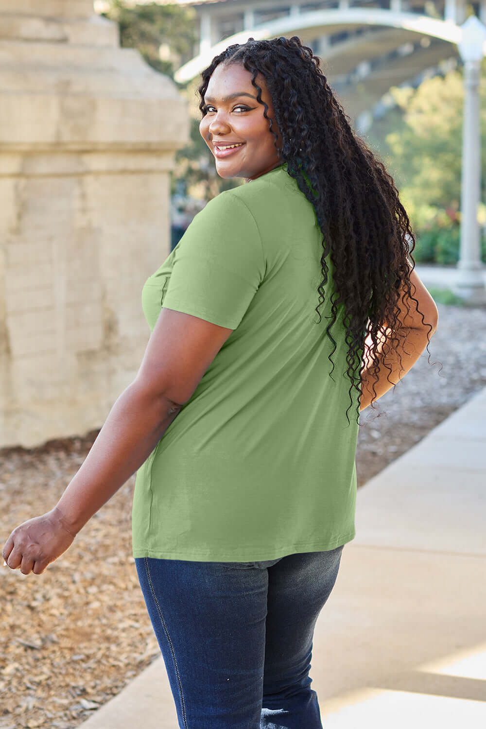 Woman wearing green Basic Bae Bamboo V-Neck Short Sleeve T-Shirt walking outdoors.