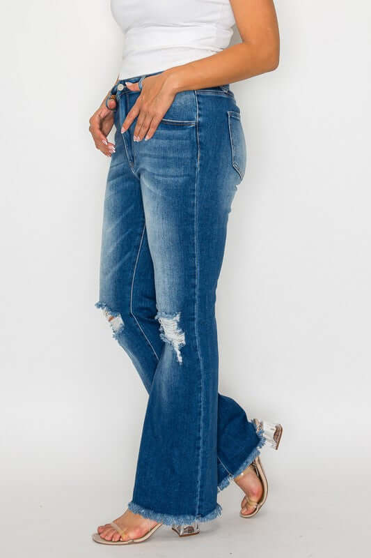 Woman wearing bytos Full Size Raw Hem Distressed High Rise Bootcut Jeans with a trendy and unique lived-in look.