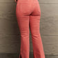 Woman wearing Bailey High Waist Side Slit Flare Jeans in pink by Risen Jeans, showcasing back view with side slit and frayed hem.