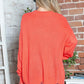 Woman wearing Bella Road Frayed Hem Sweater in vibrant orange, showcasing dropped shoulder style and playful frayed details.