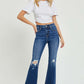 Woman wearing High Rise Distressed Crop Flare Risen Jeans with white top, showcasing trendy denim style with high rise fit and ripped detailing.