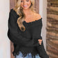 Woman wearing Bella Road frayed hem dropped shoulder sweater in black, showcasing a playful and stylish look.