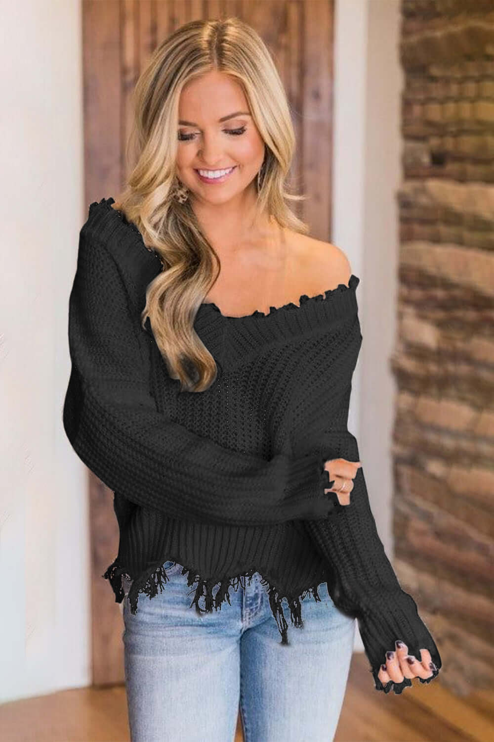 Woman wearing Bella Road frayed hem dropped shoulder sweater in black, showcasing a playful and stylish look.