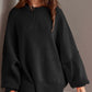 Woman wearing black Double Take Side Slit Round Neck Long Sleeve Sweater featuring a cozy, playful side slit design.