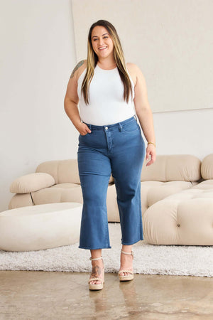 Woman modeling Crop Chloe Full Size Tummy Control High Waist Raw Hem Jeans in stylish living room