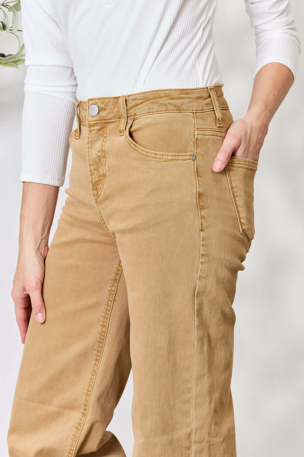 Woman modeling Risen Fringe Hem Wide Leg Jeans in beige with pocket details. High-waisted, flattering fit.