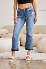 Woman wearing release hem cropped bootcut Judy Blue Jeans paired with white high heels, showcasing trendy denim style.