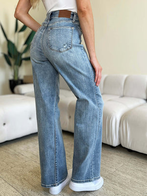 Woman wearing High Waist Straight Judy Blue Jeans, showing back details and fit, with white shoes and a casual indoor setting.