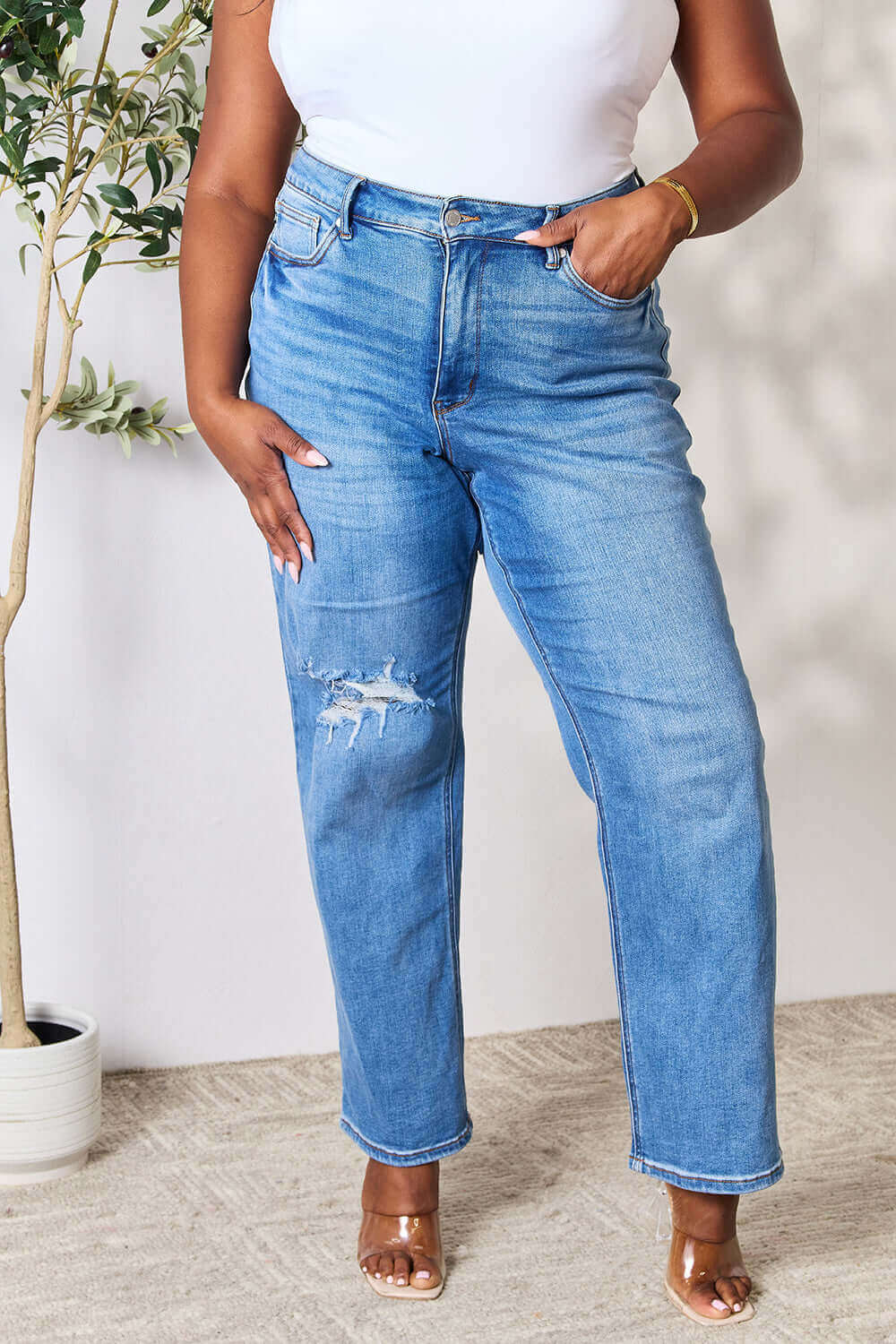 Plus-size model wearing high waist distressed jeans by Judy Blue Jeans in medium blue, showcasing the comfortable and stylish fit.