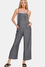 Woman in washed adjustable strap wide leg denim overalls, exuding casual chic style with a modern twist.