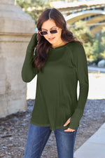 Woman wearing round neck long sleeve t-shirt in forest green paired with jeans, standing outdoors with sunglasses.