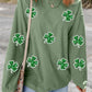 Stylish woman wearing a green long sleeve sweatshirt with sparkling sequin clovers, perfect for casual outings.