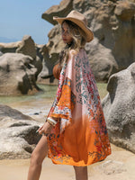 Stylish woman wearing Bella Road printed long sleeve cover-up on the beach with colorful patterns and a floppy hat.