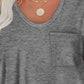 Woman wearing Bella Road Round Neck Long Sleeve T-Shirt with a pocket, necklace visible, and slightly stretchy gray fabric.