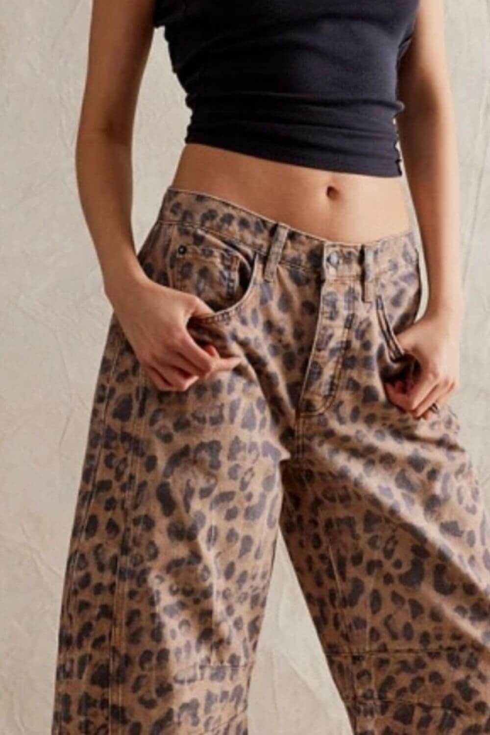 Woman wearing wide leg jeans with pockets in leopard print, showcasing buttoned closure and high waist.