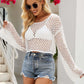 Woman wearing an openwork round neck long sleeve cover-up in white, paired with denim shorts and sunglasses.