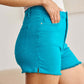 Tummy Control High Waist Raw Hem Denim Shorts by RFM Jeans in bright turquoise, showcasing smooth and flattering fit.