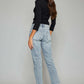 Woman wearing high waist button fly raw hem cropped straight jeans with black top and beige sandals, showcasing the back view.