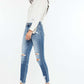 Woman wearing high rise frayed ankle skinny jeans in medium wash with distressed details and fray hem, paired with white blouse and heels