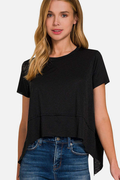 Woman wearing a black Slit High-Low Round Neck T-Shirt with side slits and trendy high-low hem, paired with blue jeans for a stylish look