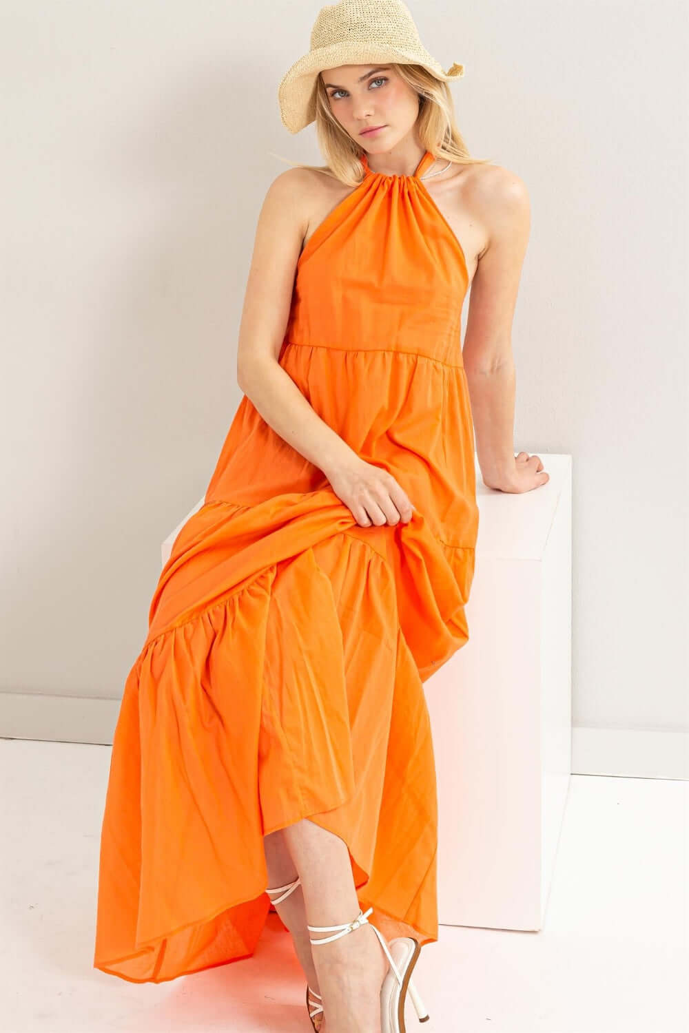 Model in orange halter neck cover up maxi dress, featuring a tiered silhouette and open back, perfect for summer vibes.