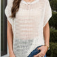 Woman wearing a sheer white openwork cover-up, perfect for beach or poolside lounging, paired with denim jeans.