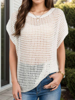 Woman wearing a sheer white openwork cover-up, perfect for beach or poolside lounging, paired with denim jeans.