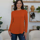 Woman wearing FAM-FAM Round Neck Long Sleeve T-Shirt in orange with decorative buttons, perfect for casual style.