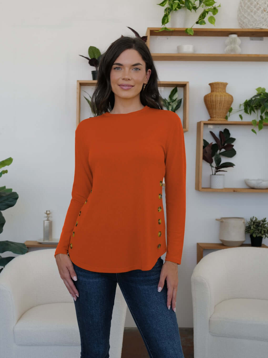 Woman wearing FAM-FAM Round Neck Long Sleeve T-Shirt in orange with decorative buttons, perfect for casual style.