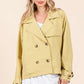 Elegant woman in yellow double-breasted trench coat, showcasing modern style and sophistication in a light outfit.