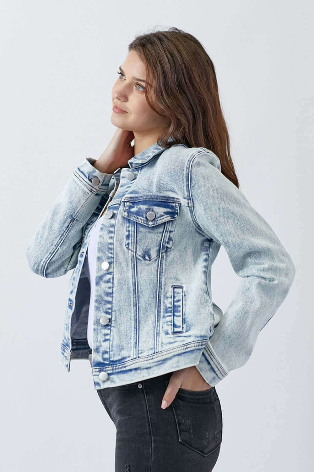 Woman wearing button-up washed denim jacket from Risen Jeans, striking a casual pose against a white background.