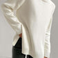 Cozy white turtleneck sweater with side slits and dropped shoulders for a chic, relaxed fit. Perfect for a stylish winter look.