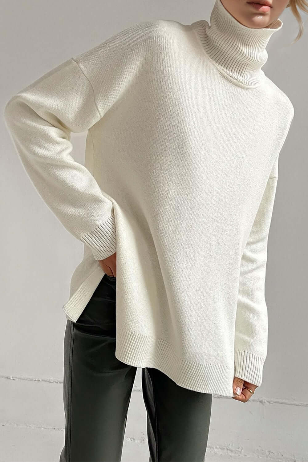 Cozy white turtleneck sweater with side slits and dropped shoulders for a chic, relaxed fit. Perfect for a stylish winter look.