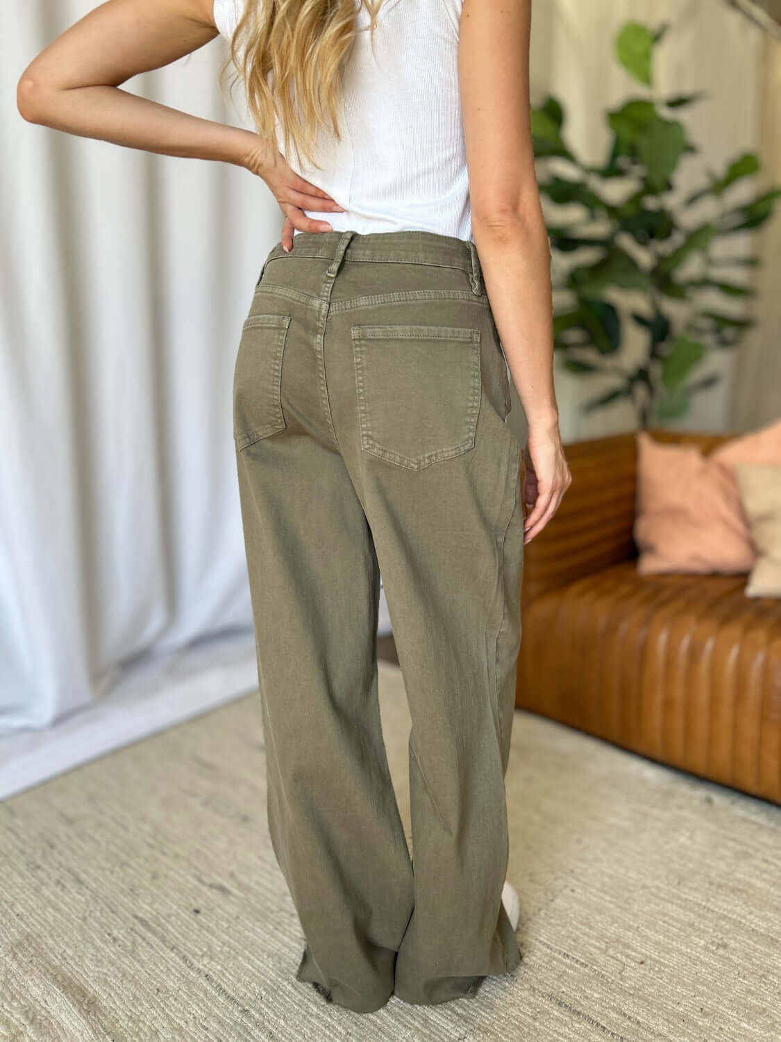 Woman wearing RFM Full Size High Rise Garment Dye Wide Leg Jeans in olive green, showcasing back pockets and high-waist fit.