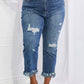 Woman wearing Undone Chic Straight Leg Risen Jeans with distressed details, raw hem, and high-waist, paired with a crop top and green sandals